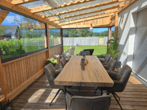 Sommergarten Innenansicht mit großen Holztisch und Ausblick in schönen Garten